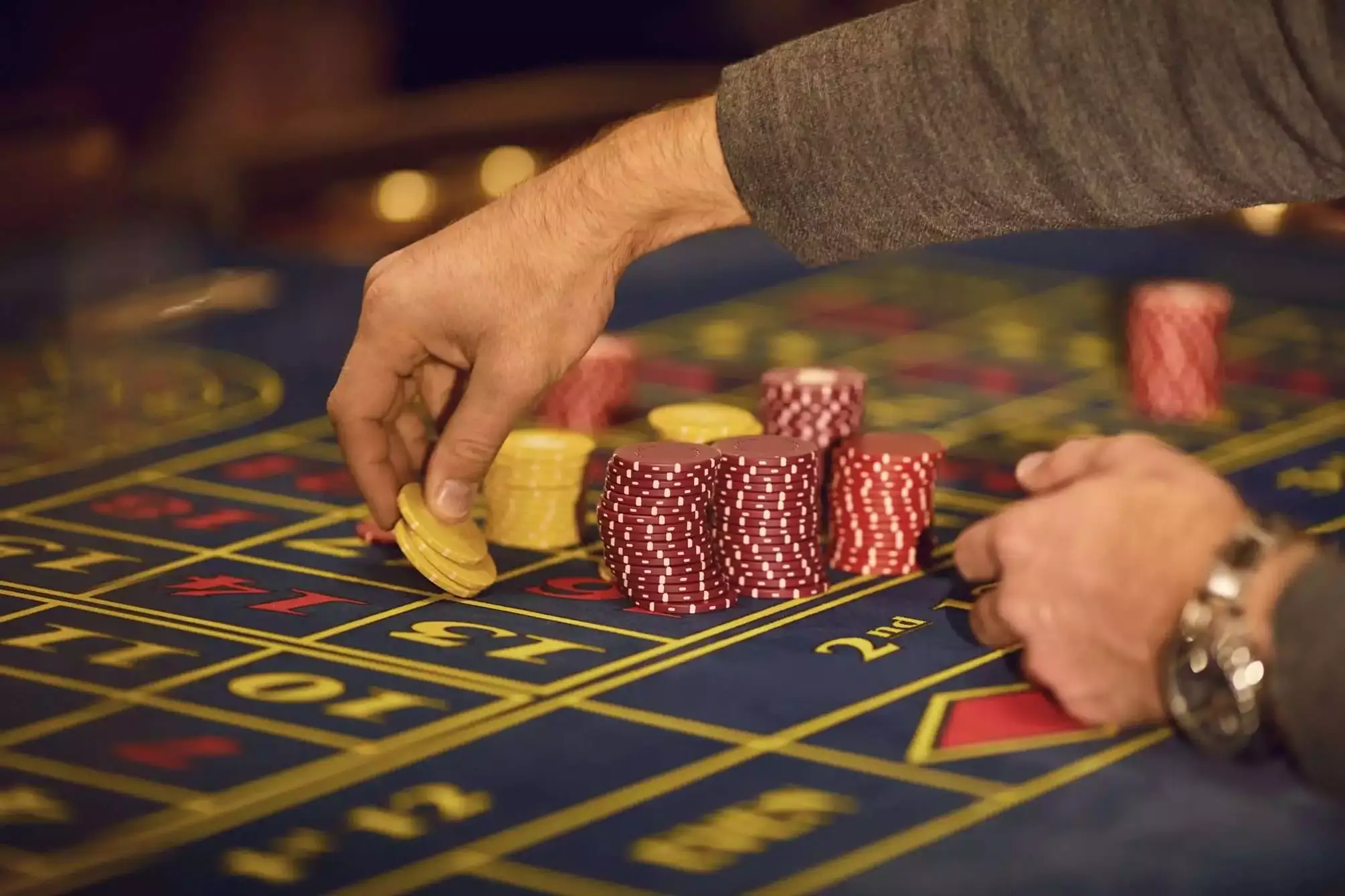A player plays roulette in a casino. Close-up hand with chips on a roulette table. Gambling.Casino game concept.