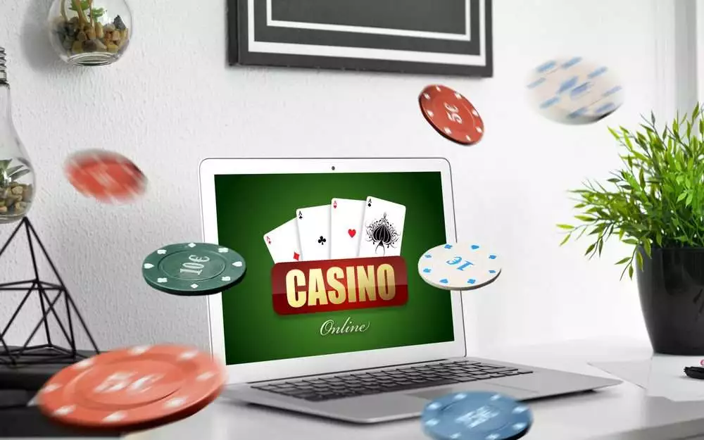Text CASINO ONLINE on screen of laptop on table in room.